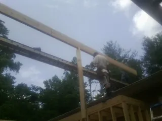 Carpenter setting a ridge beam over a new addition frame — Ice Dam Removal by Roofing Brothers in Port Byron