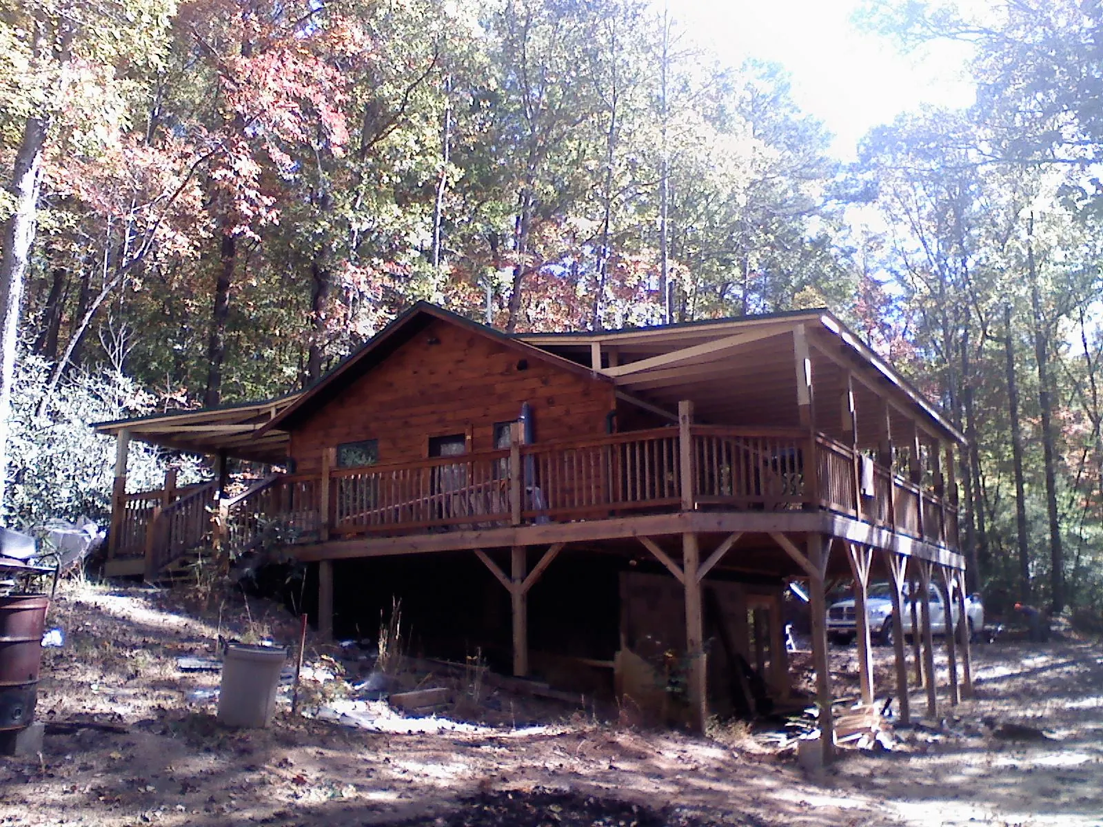 Log cabin with a wraparound porch and metal roof in the fall in Port Byron