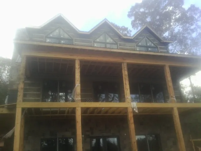 Dormers and porch framing on a large log home under construction — Roof Coating work by our crew in Port Byron