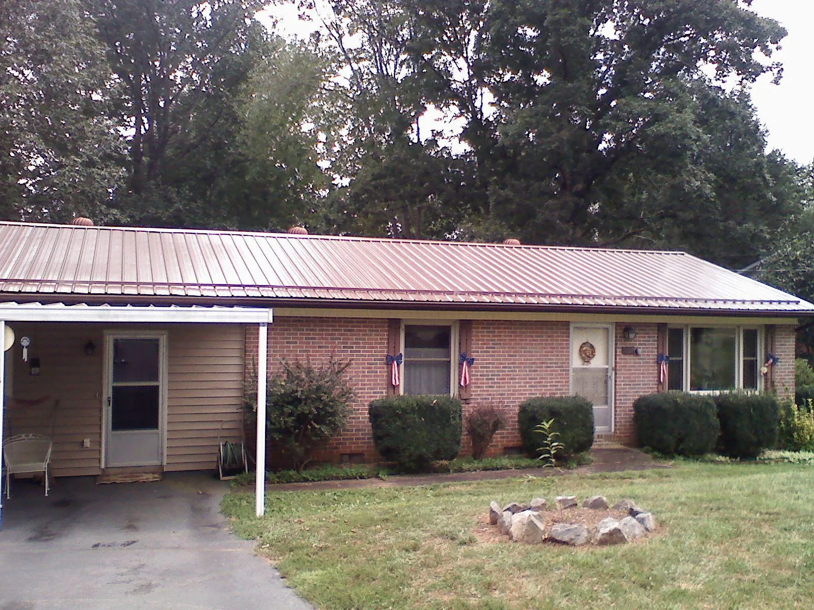 Bronze metal roof and carport on a brick ranch home — Roof Repair work by our crew in Port Byron