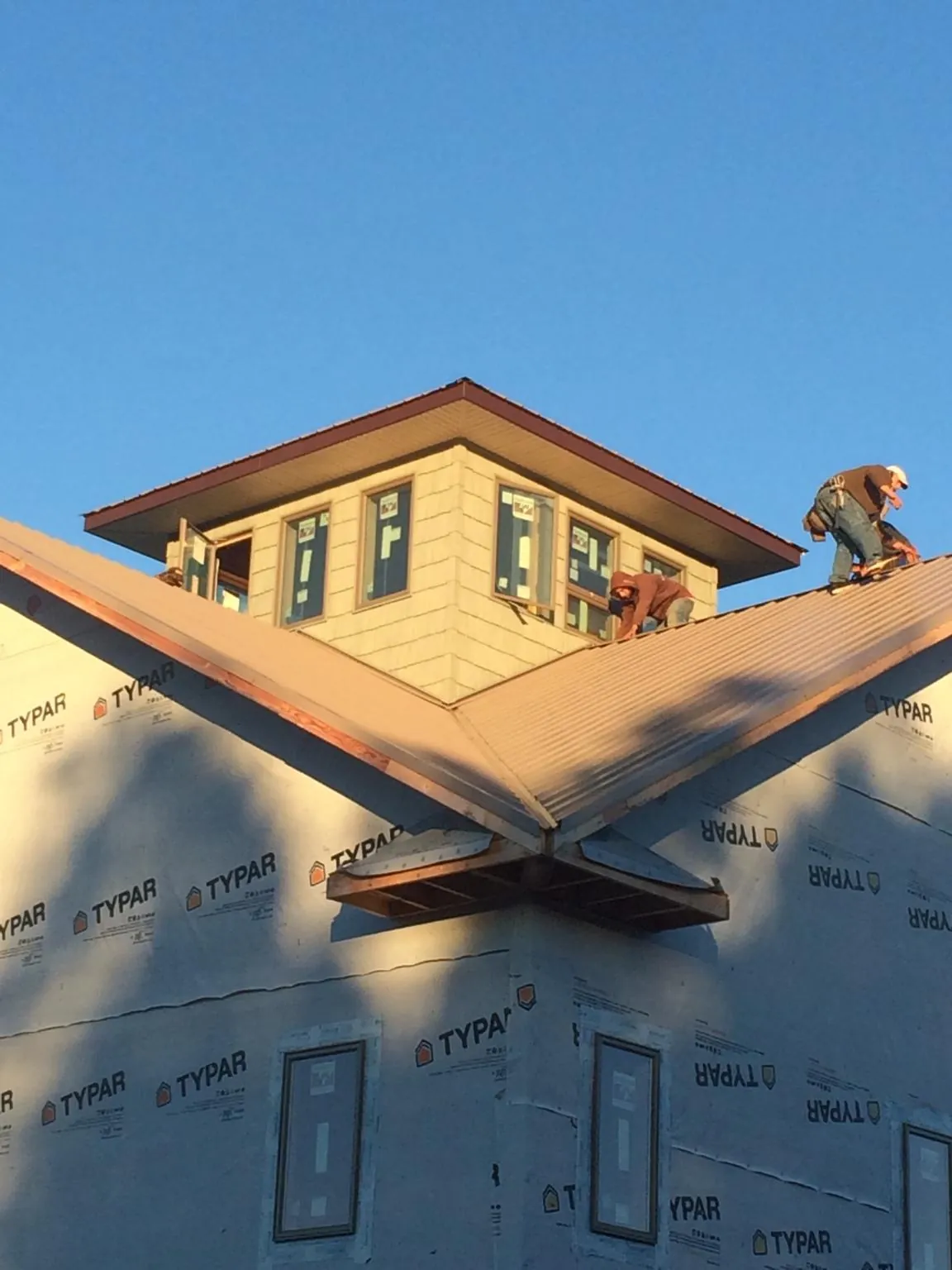 Roofers working around a rooftop cupola on a new metal roof at sunset — Roof Waterproofing in Port Byron by Roofing Brothers